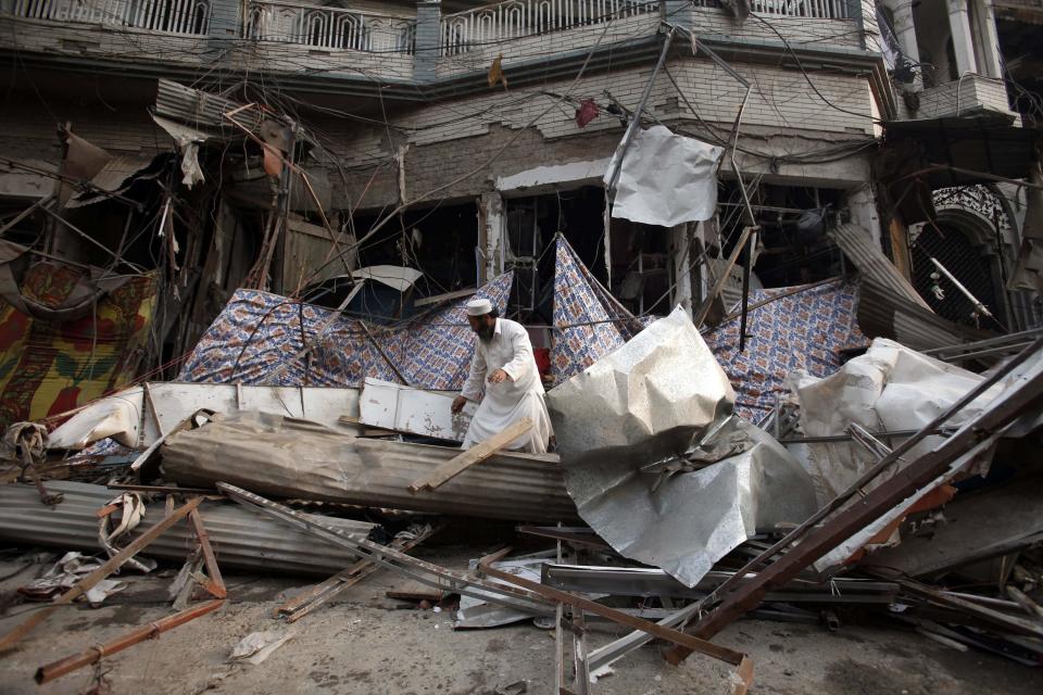 A shopkeeper collects his belongings from the debris of a damaged building after it was hit by a bomb blast, which happened on Sunday, in Peshawar