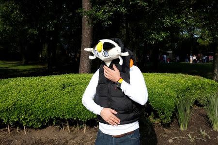 A man covers his face with a stuffed toy of a Pokemon character, Meowth, during a gathering to celebrate "Pokemon Day" at chapultepc park in Mexico City, Mexico August 21, 2016. REUTERS/Carlos Jasso