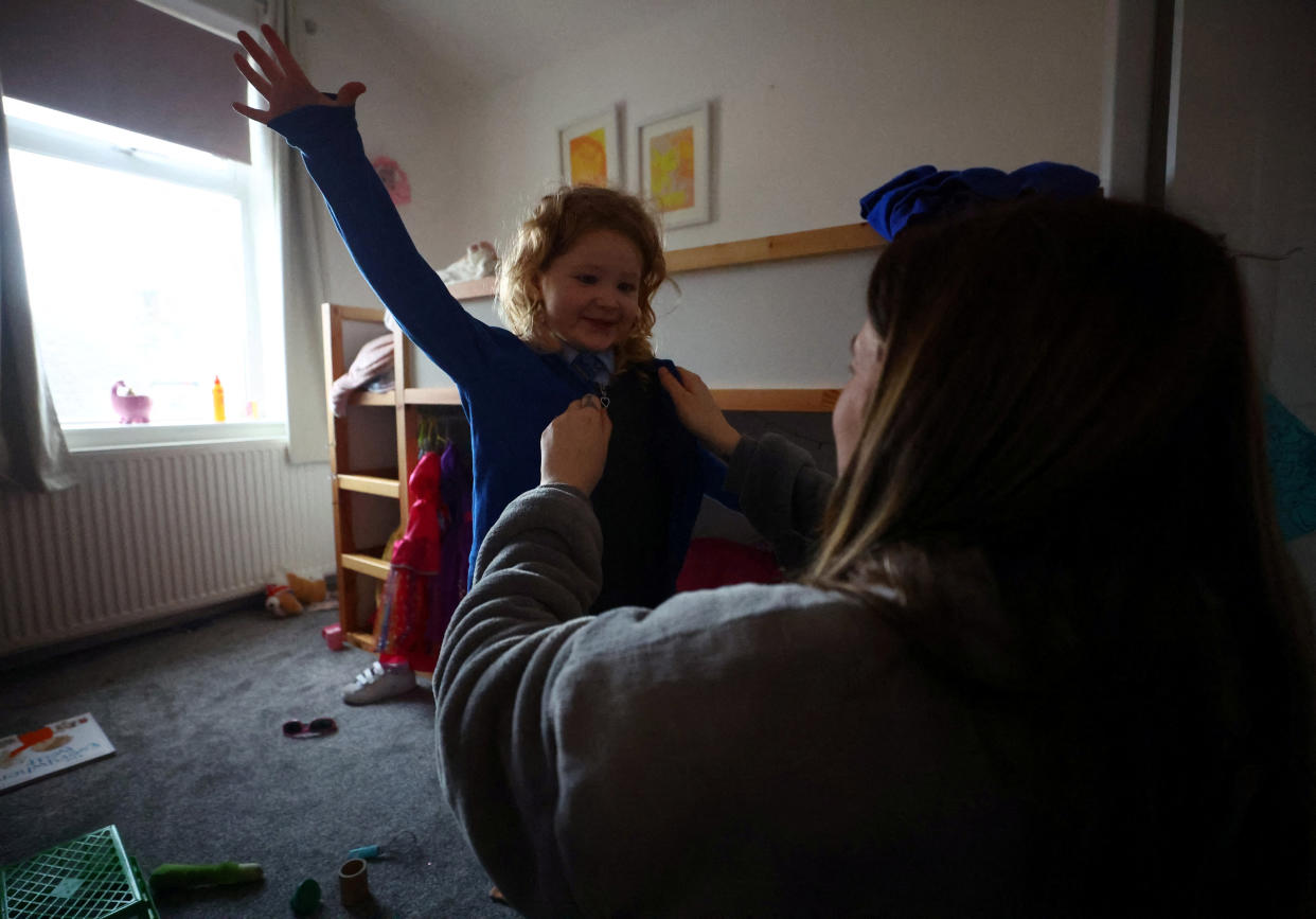 Louise Sharples, 35, helps her daughter Lola, 4, get dressed for school at their home in Clitheroe, East Lancashire, Britain, March 2, 2023. REUTERS/Hannah McKay