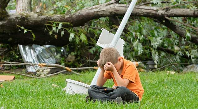 A young boy sits in the grass holding his head in front of a destroyed house after a tornado touched down overnight in Van, Texas. Photo: AP