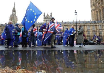 Anti-Brexit protesters are reflected in a puddle as they demonstrate opposite the Houses of Parliament in London, Britain, April 30, 2018. REUTERS/Simon Dawson/File Photo