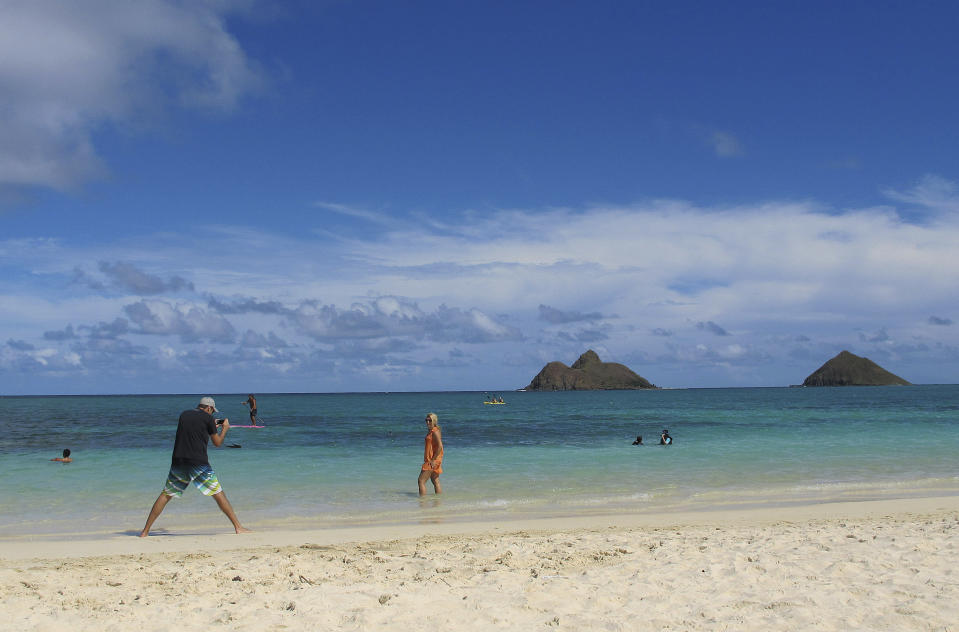 FILE - This Oct. 29, 2013 file photo shows tourists on Lanikai Beach in Kailua, Hawaii. Airbnb is pushing back against Hawaii's attempt to find tax delinquents by subpoenaing 10 years' worth of invoices, receipts and other records from the home-sharing platform's island hosts, calling it an unprecedented, "massive intrusion" that violates state and federal law. (AP Photo/Audrey McAvoy)