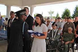 Justine Newman accepts the flag that draped the cremated remains of 14 unclaimed veterans including nine from Chester County that she identified.