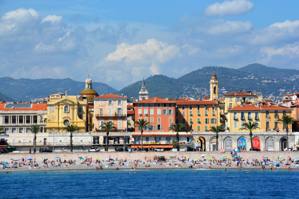 Nice city  view from a boat. View of the Promenade des Anglais, the mountains , the beach  and its beautiful buildings. Nice is a city located in the department of Alpes maritimes on the french riviera in South east of France . 
it was a summer day in august and the beach was crowded