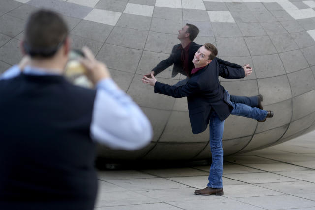Tyler Ribeiro from Tulare, Cailf., poses at Anish Kapoor's stainless steel sculpture Cloud Gate, also known as "The Bean," during a visit with co-workers to Chicago's Millennium Park Thursday, May 25, 2023. Chicago is heading into the Memorial Day weekend hoping to head off violence that tends to surge with rising temperatures of summer. (AP Photo/Charles Rex Arbogast)