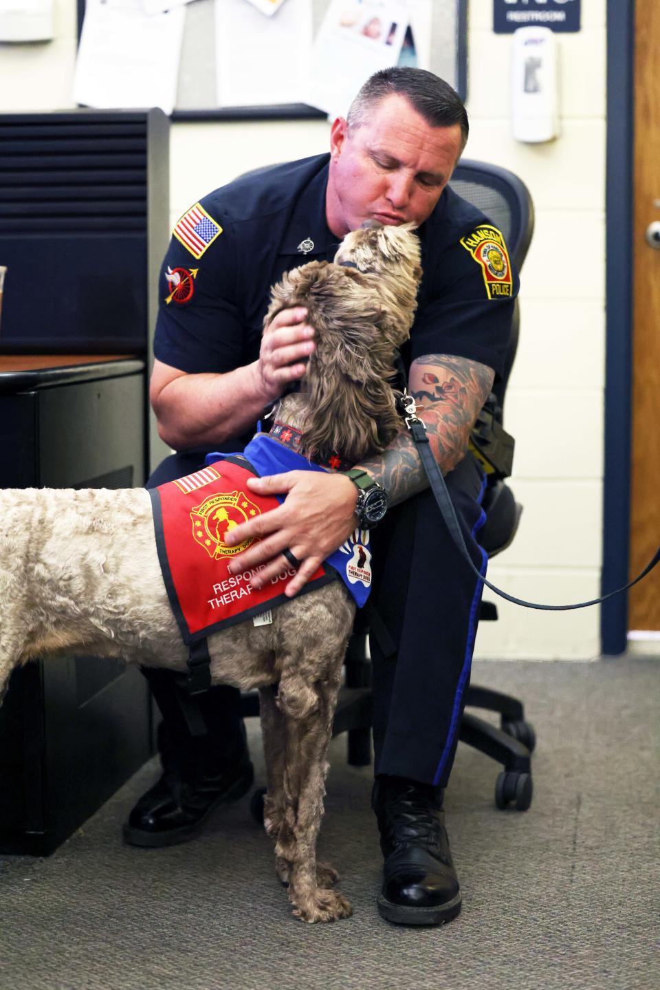 Hanson Police Sergeant Leo Arseneau greets Sparkie, a 2-year-old labradoodle and first responder therapy dog from East Bridgewater on Wednesday, May 4, 2022.