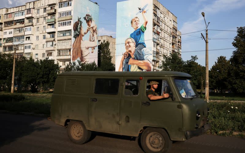 Militares ucranianos pasan por delante de una pintada de una familia en los edificios dañados en Bajmut