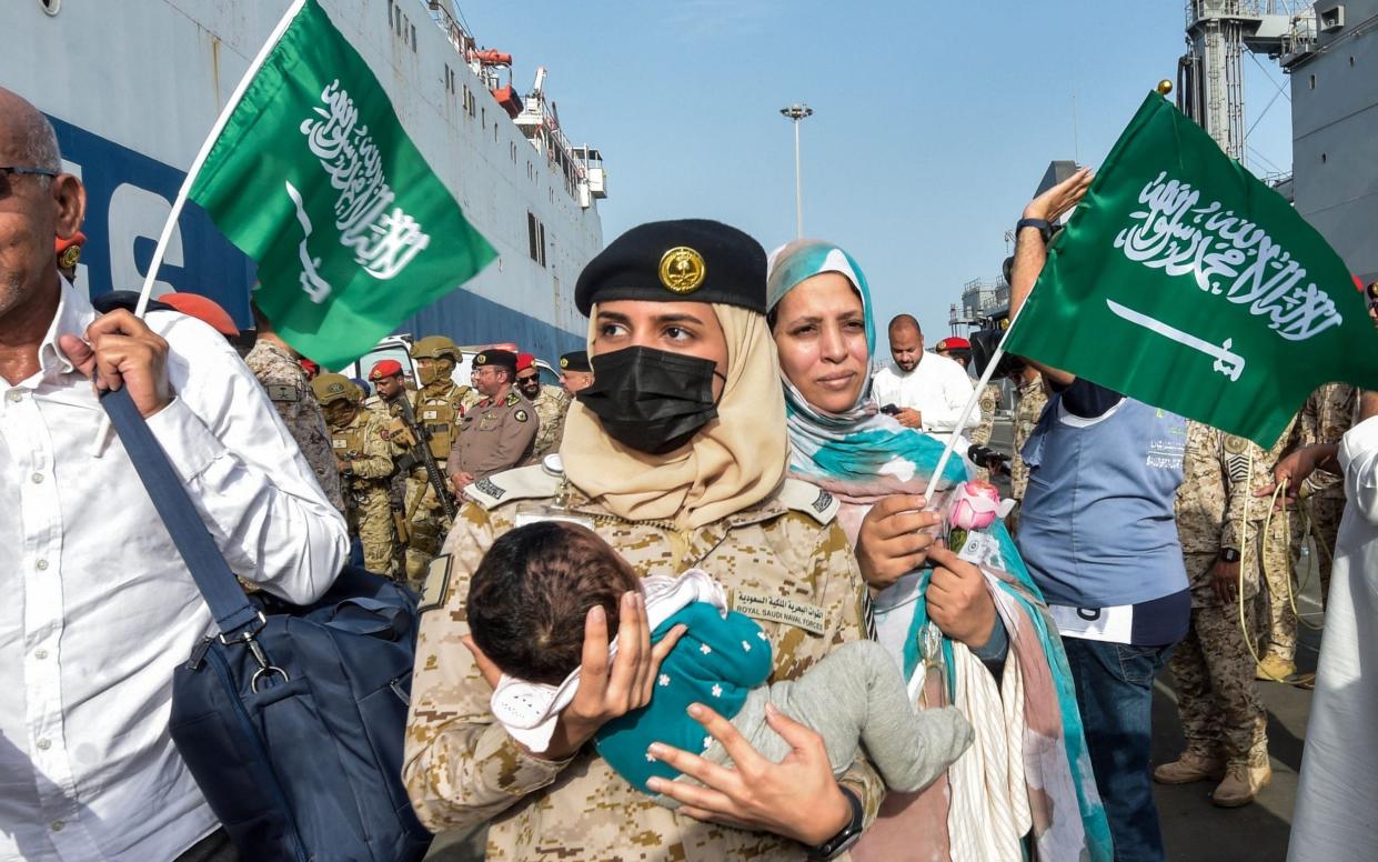 A Saudi Navy sailor carries a child as evacuees arrive at King Faisal Navy Base in Jeddah on April 26, 2023 - AMER HILABI