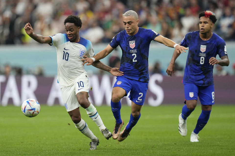 Sergino Dest of the United States, centre, challenges for the ball with England's Raheem Sterling during the World Cup group B soccer match between England and The United States, at the Al Bayt Stadium in Al Khor, Qatar, Friday, Nov. 25, 2022. (AP Photo/Andre Penner)