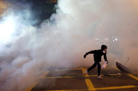 An anti-extradition demonstrator runs away from tear gas in Hong Kong