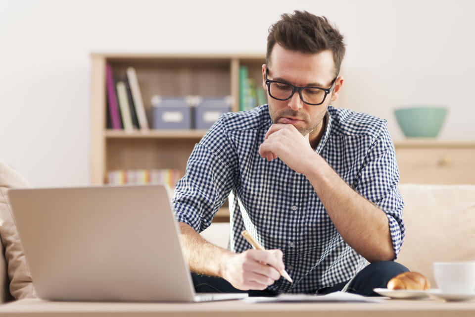 Man at laptop holding pen