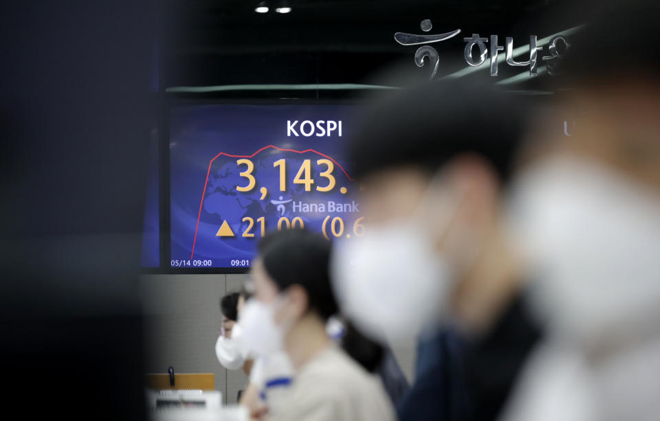 A currency trader watch computer monitors near the screen showing the Korea Composite Stock Price Index (KOSPI) at the foreign exchange dealing room in Seoul, South Korea, Friday, May 14, 2021. Asian shares rose Friday after Wall Street put the brakes on a three-day losing streak with a broad stock market rally powered by Big Tech companies and banks. (AP Photo/Lee Jin-man)