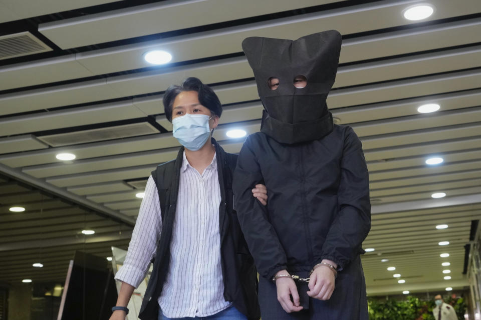 A hooded suspect is accompanied by a police officer to search evidence at office in Hong Kong Thursday, July 22, 2021. Hong Kong's national security police on Thursday arrested five people from a trade union of the General Association of Hong Kong Speech Therapists on suspicion of conspiring to publish and distribute seditious material, in the latest arrests made amid a crackdown on dissent in the city. (AP Photo/Vincent Yu)