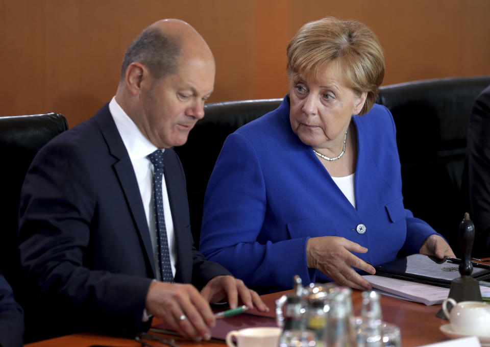 German Chancellor Angela Merkel, right, and German Finance Minister Olaf Scholz, left, talk as they arrive for the weekly cabinet meeting at the Chancellery in Berlin, Germany, Wednesday, Aug. 21, 2019. The German government sold 30-year bonds at a negative interest rate Wednesday Aug. 21, 2019, in a sign of the clouds over markets and future growth as well as increased expectations that more central bank stimulus is likely on the way.(AP Photo/Michael Sohn)