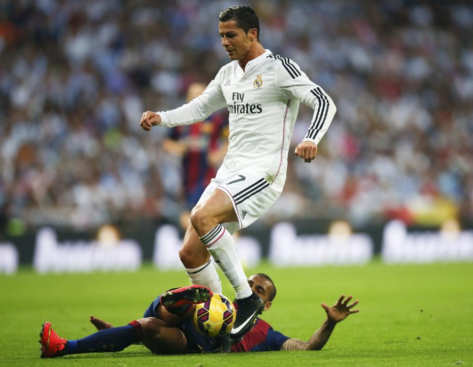 Barcelona's Daniel Alves (bottom) tackles Real Madrid's Cristiano Ronaldo during their Spanish first division "Clasico" soccer match at the Santiago Bernabeu stadium in Madrid October 25, 2014. REUTERS/Sergio Perez (SPAIN - Tags: SOCCER SPORT)
