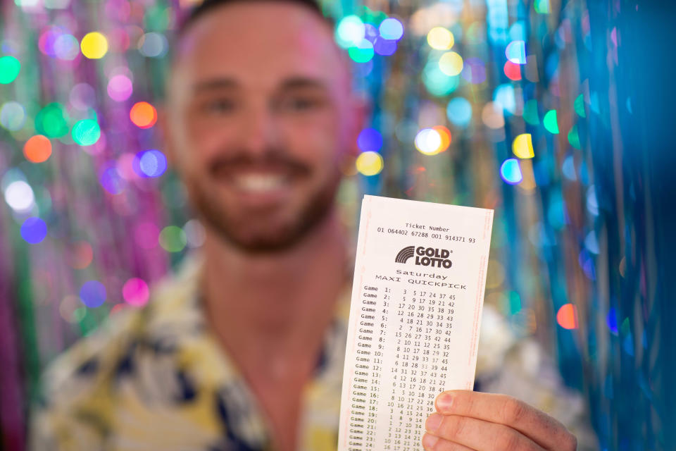 Man holding Gold Lotto ticket. 