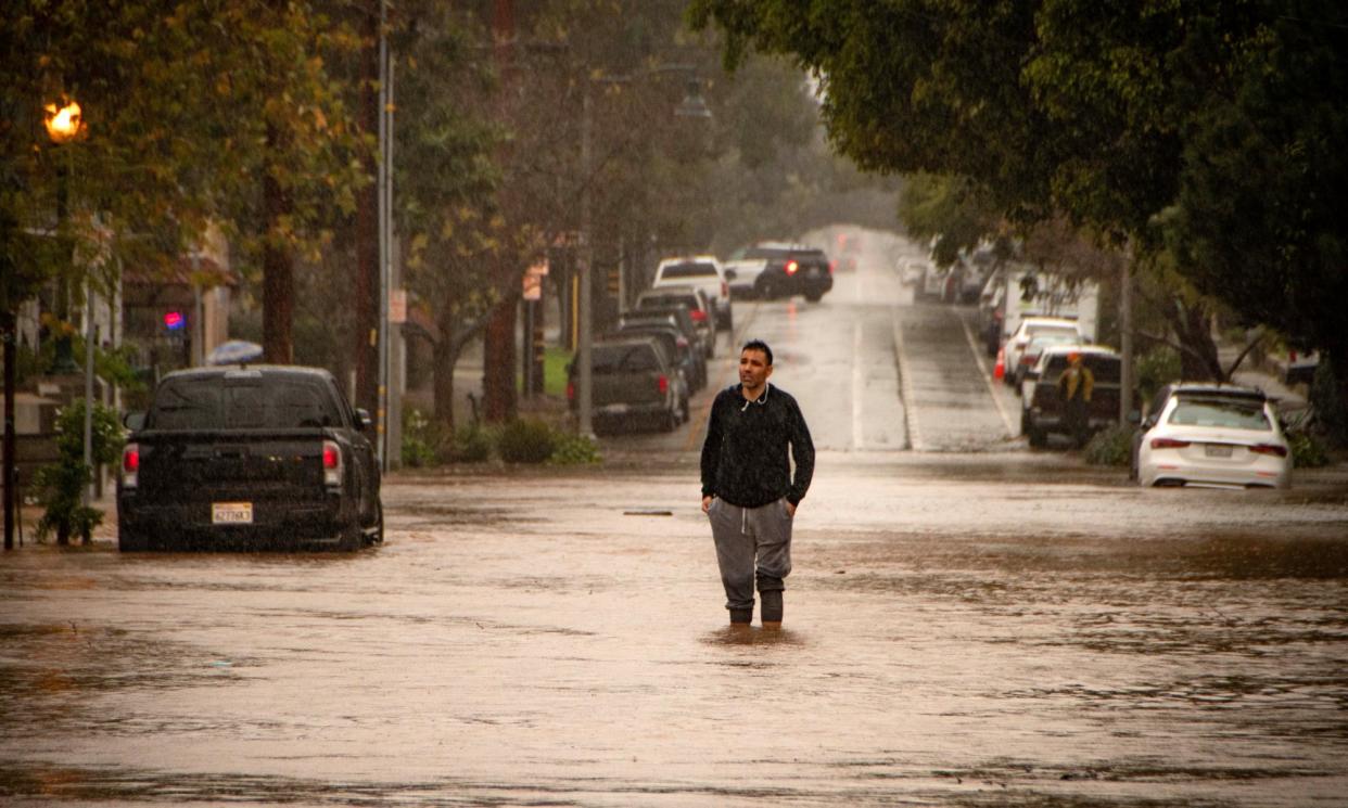 <span>A man stands in the middle of a flooded street in Santa Barbara, California, on 4 February 2024.</span><span>Photograph: Erick Madrid/EPA</span>