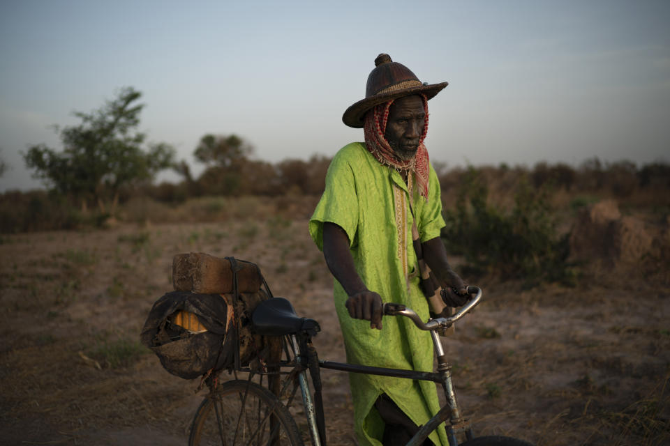 In this Nov. 25, 2018 photo, Cheikh Fofana pushes his bicycle after working on a peanut field as the sun sets in Goudiry, Senegal. Fofana grieves for his son, Tidiane, even while refusing to officially acknowledge he is dead. Tidiane was one of 18 children; though the only one who noticed when his aging father or widowed aunt needed help. It was Tidiane who wanted to reach Europe to earn enough so that Fofana would never again have to ride his bicycle to the family's fields to work. (AP Photo/Felipe Dana)