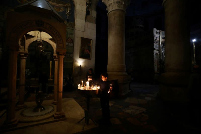 FILE PHOTO: A boy lights candles in the Church of the Holy Sepulchre in Jerusalem's Old City