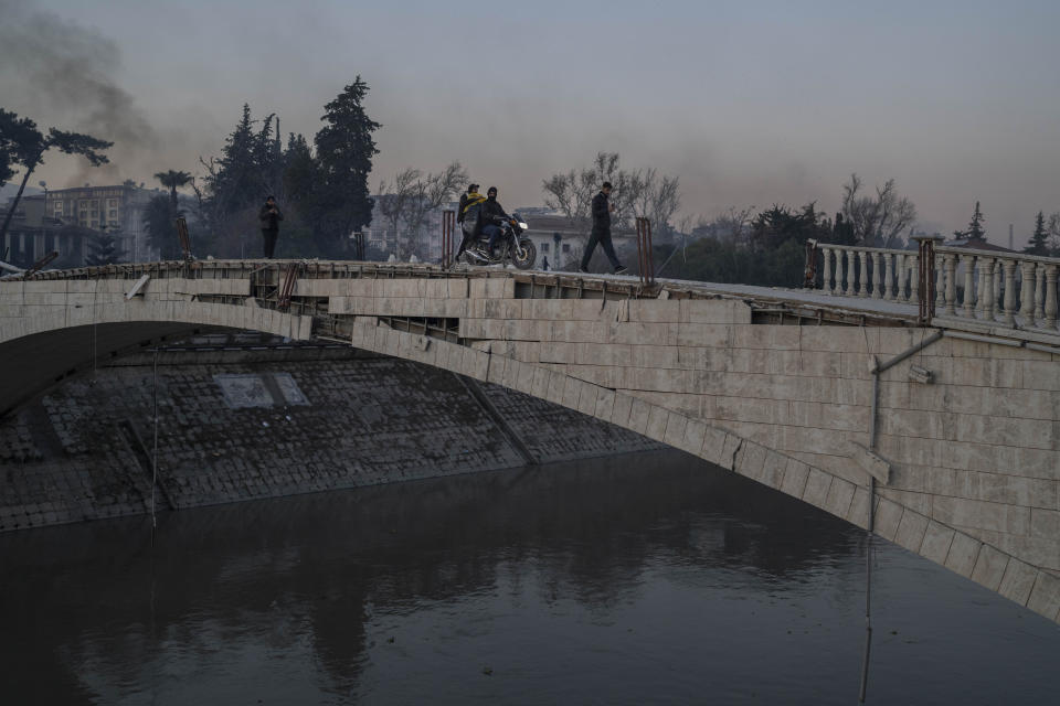 People cross a bridge damaged during an earthquake in Antakya, southeastern Turkey, Monday, February 13, 2023. Thousands left homeless by a massive earthquake that struck Turkey and Syria a week ago packed into crowded tents or lined up in the streets Monday for hot meals as the desperate search for survivors entered what was likely its last hours. (AP Photo/Bernat Armangue)