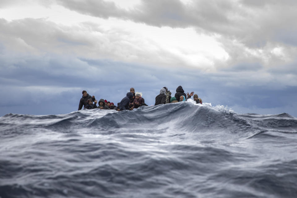 Men from Morocco and Bangladesh react on an overcrowded wooden boat, as aid workers of the Spanish NGO Open Arms approach them in the Mediterranean Sea, international waters, off the Libyan coast, Friday, Jan. 10, 2020. (AP Photo/Santi Palacios)