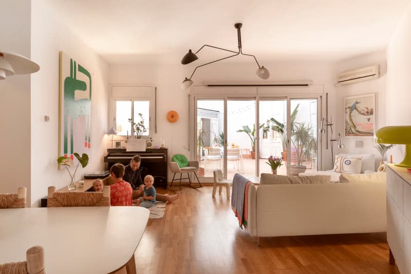 family sitting on small rug in large white living room