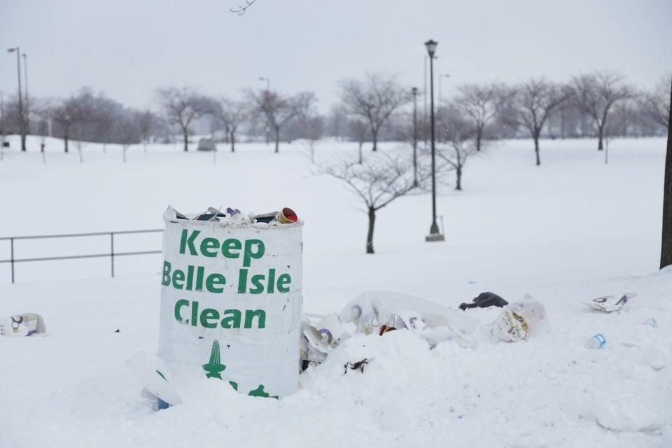 Trash fills the snowy area around a trash can on Belle Isle on Monday Feb. 10, 2014, during the first day the park in Detroit became a state park.