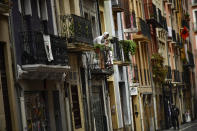 Un vecino de Pamplona se asoma desde su balcón a la calle, por la que solo camina una persona. (Foto: Alvaro Barrientos / AP).