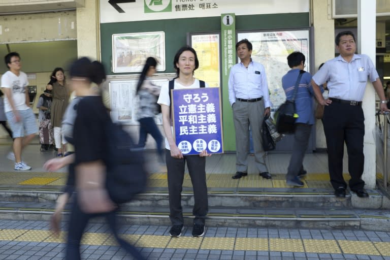 A man stands with a placard "Protect it, Constitutionalism, Pacifism, Democracy" at an election campaign by the main opposition party in Tokyo