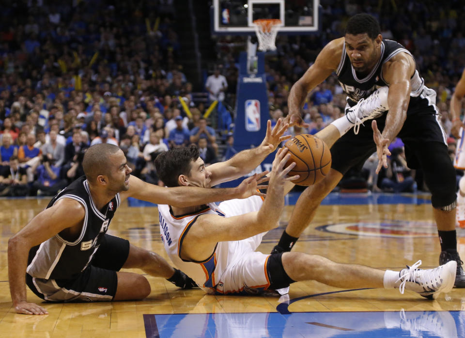 Oklahoma City Thunder forward Nick Collison (4) passes from between San Antonio Spurs guard Tony Parker, left, and forward Tim Duncan during the third quarter of an NBA basketball game in Oklahoma City, Thursday, April 3, 2014. Oklahoma City won 106-94. (AP Photo/Sue Ogrocki)