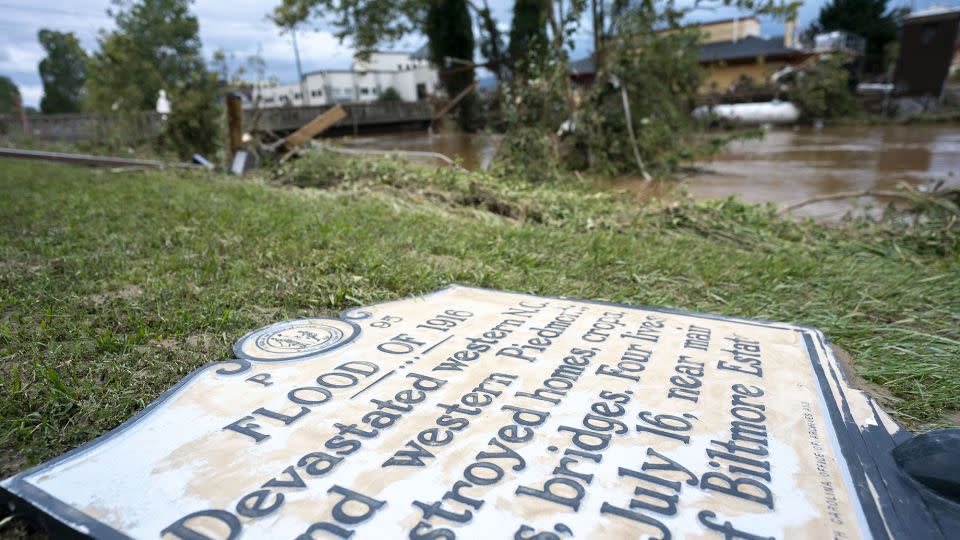 A sign commemorating the 1916 flood lies on the ground next to a flooded waterway near Biltmore Village. -Sean Rayford/Getty Images