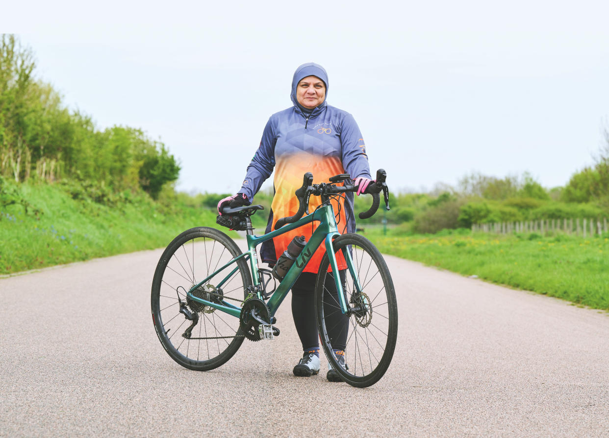  Iffat Tejani, wearing a modest cycling jersey, standing with her bike 