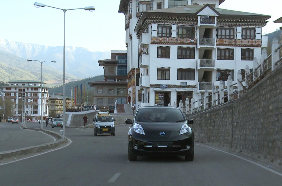 In this undated photo released Friday, Feb. 21, 2014 by Nissan Motor Co., the Japanese automaker's electric car Leaf, right, runs in Thimphu in Bhutan. The Himalayan kingdom of Bhutan and Nissan are partnering on electric cars, with the Japanese automaker's Leaf being chosen for the government fleet and taxis. Under a deal announced Friday, Feb. 21, 2014, Nissan will help Bhutan achieve its goal of becoming a zero-emissions nation. (AP Photo/Nissan Motor Co.)