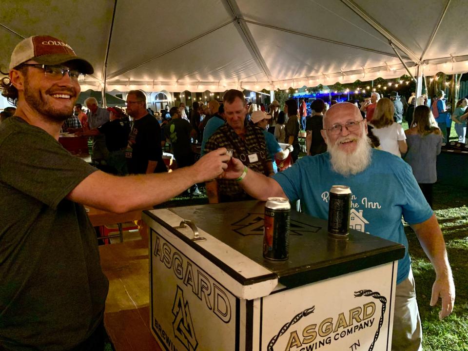 Ray Turner, right, serves up brews from Columbia's local Asgard Brewing Co. & Taproom, who were the main organizers for Friday's Oktoberfest event.  Oktoberfest featured nearly a dozen regional breweries and raised more than $40,000 for Columbia's local Room in The Inn shelter. (Staff photo by Jay Powell)