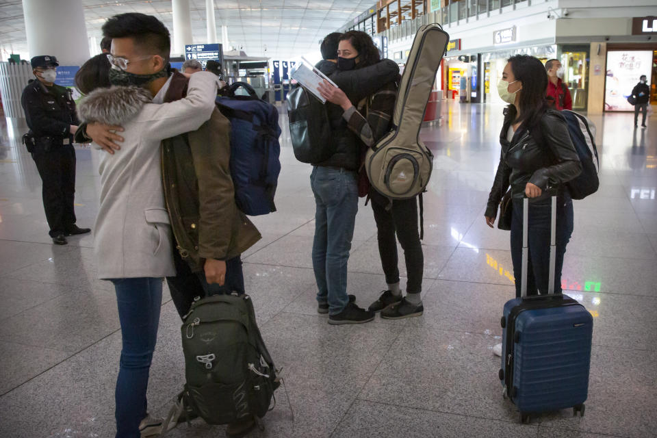 FILE - Wall Street Journal reporters, from right, Stephanie Yang, Julie Wernau, and Stu Woo embrace colleagues before their departure at Beijing Capital International Airport in Beijing on March 28, 2020. China and the U.S. have agreed to ease restrictions on each other's media workers amid a slight easing of tensions between the two sides. The announcement in the official China Daily newspaper on Wednesday, Nov. 17, 2021 said the agreement was reached ahead of Tuesday's virtual summit between Chinese leader Xi Jinping and U.S. President Joe Biden. (AP Photo/Mark Schiefelbein, File)