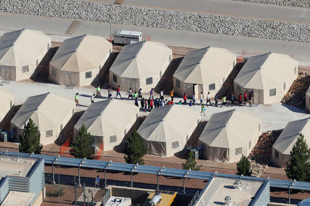 Immigrant children, many of whom have been separated from their parents under a new "zero tolerance" policy by the Trump administration, are shown walking in single file between tents in their compound next to the Mexican border in Tornillo, Texas, U.S. June 18, 2018. REUTERS/Mike Blake