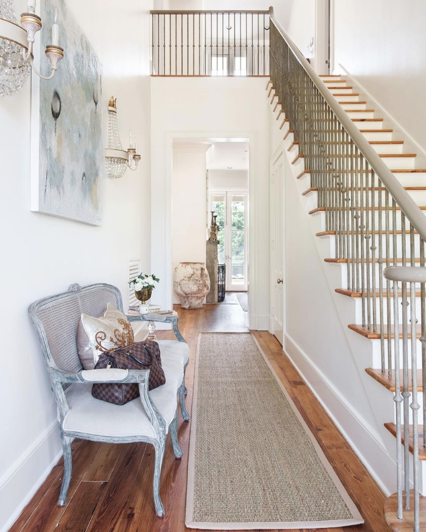 Entryway with bench with handbag on and rug.