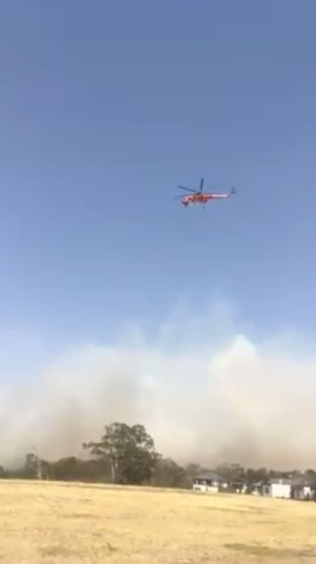 A water bomber helicopter flies over as the bushfires continue in Bundoora