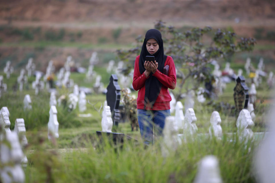 A Muslim woman prays at the grave of a relative at a cemetery reserved for those who died of COVID-19, in Medan, North Sumatra, Indonesia, Thursday, March 31, 2022. Prior to the holy fasting month of Ramadan that is expected to begin on Sunday, Muslims followed local tradition to visit cemeteries to pray for their deceased loved ones. (AP Photo/Binsar Bakkara)