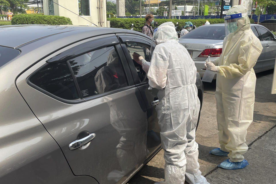 Medical workers conduct swab tests on passengers at a drive-thru COVID-19 testing facility outside a hospital in Nonthaburi, Thailand Saturday, April 10, 2021. Thai authorities struggled to contain a growing coronavirus outbreak just days before the country's traditional Songkran New Year's holiday, when millions of people travel. (AP Photo/Kiko Rosario)