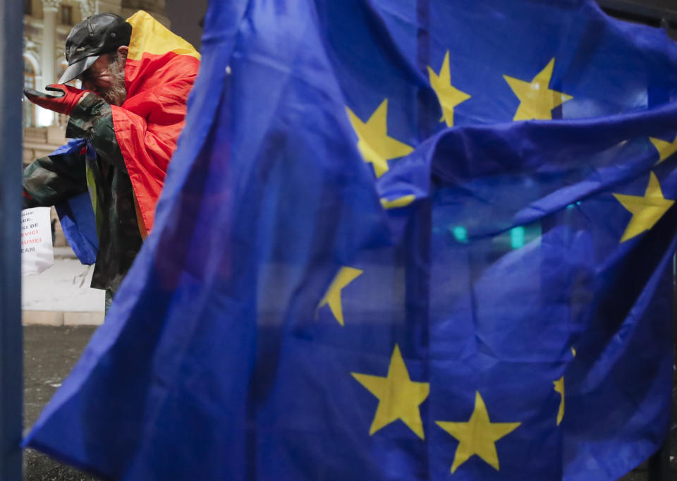 An anti-government protester adjusts his gloves outside the Romanian Atheneum concert hall in Bucharest, Romania, Thursday, Jan. 10, 2019, the venue for an event marking the official start of the Romanian Presidency of the Council of the European Union. (AP Photo/Vadim Ghirda)