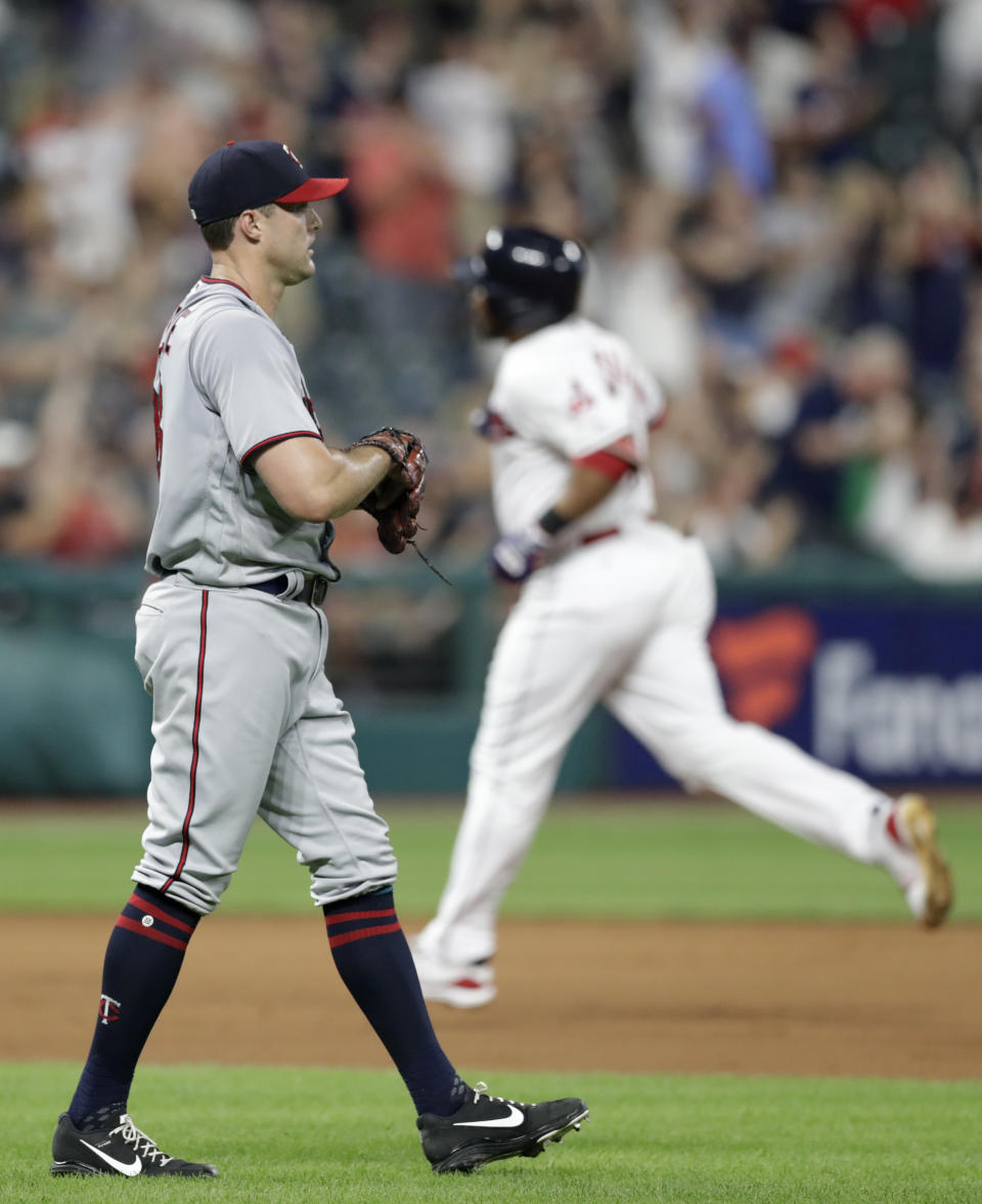 Minnesota Twins' Matt Belisle, left, waits for Cleveland Indians' Edwin Encarnacion to run the bases after hitting a three-run home run in the seventh inning of a baseball game, Monday, Aug. 6, 2018, in Cleveland. (AP Photo/Tony Dejak)