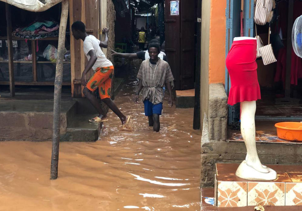 People walk through a flooded path leading to a shop during floods due to heavy rain in Pemba, Mozambique, Sunday , April 28, 2019. Serious flooding began on Sunday in parts of northern Mozambique that were hit by Cyclone Kenneth three days ago, with waters waist-high in areas, after the government urged many people to immediately seek higher ground. Hundreds of thousands of people were at risk. (AP Photo/Tsvangirayi Mukwazhi)