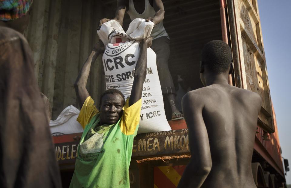 FILE - In this Thursday, Jan. 2, 2014 file photo, a man unloads food assistance supplied by the International Red Cross which arrived in the morning by truck to help the thousands who fled the recent fighting between government and rebel forces in Bor by boat across the White Nile, in the town of Awerial, South Sudan. U.N. Secretary-General Ban Ki-moon on Wednesday, Jan. 15, 2014 strongly condemned the commandeering of humanitarian vehicles and the theft of food and other desperately needed aid by government and anti-government forces in violence-torn South Sudan. (AP Photo/Ben Curtis, File)