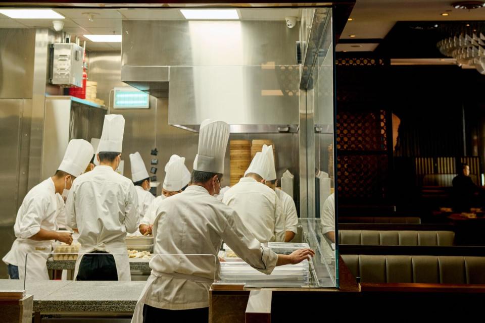 Chefs make dumplings, seen through a viewing window in the dining lounge at Paradise Dynasty.