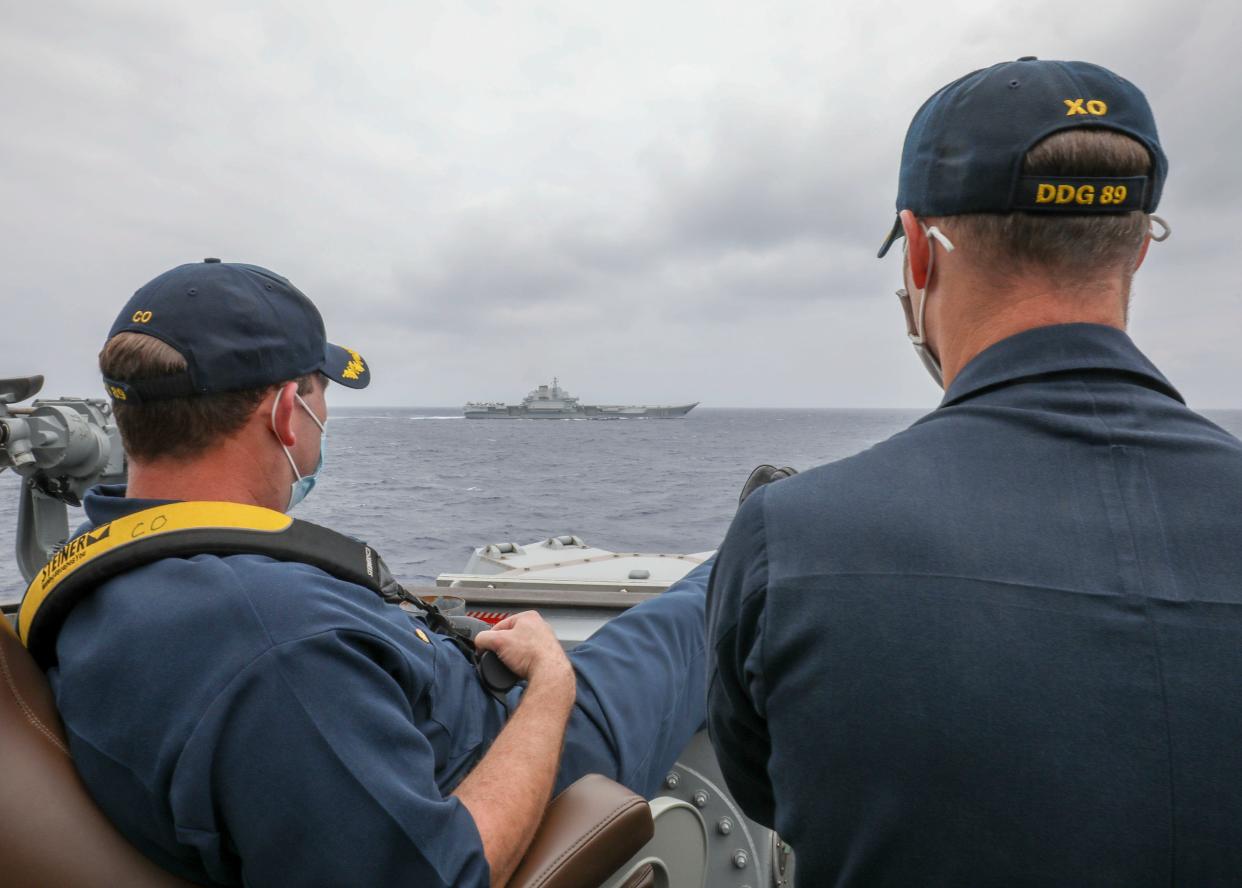 <p>Two US Navy officers look relaxed as they eye a Chinese aircraft carrier in the South China Sea</p> (US Navy)