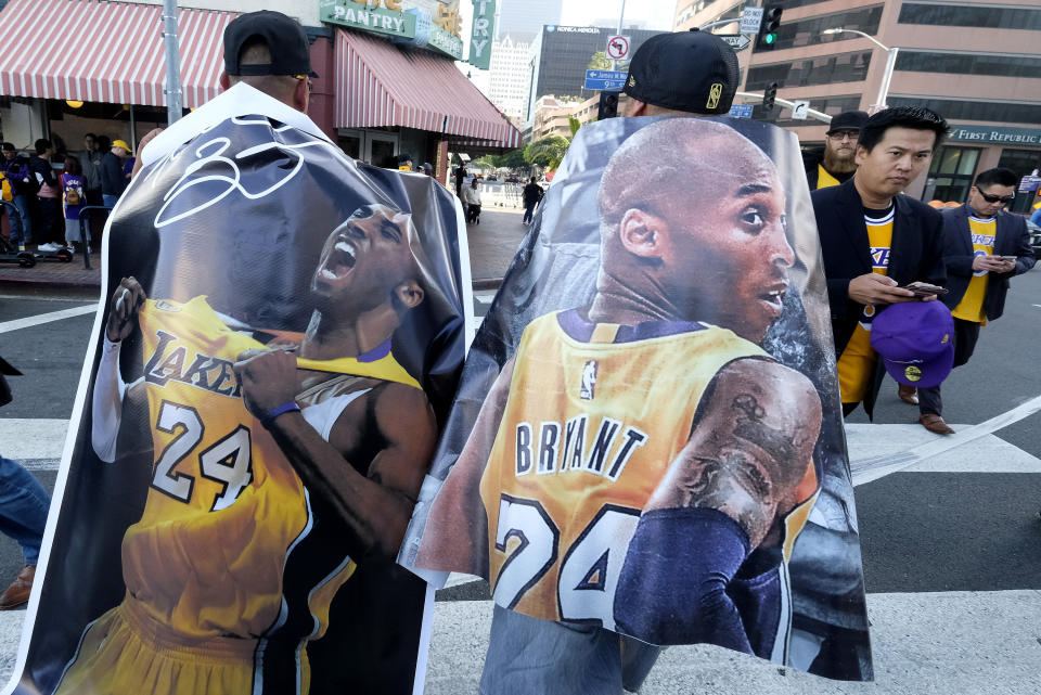 Fans carry posters of Kobe Bryant near the Staples Center before a public memorial for former Los Angeles Lakers star Kobe Bryant and his daughter, Gianna, in Los Angeles, Monday, Feb. 24, 2020. (AP Photo/Ringo H.W. Chiu)