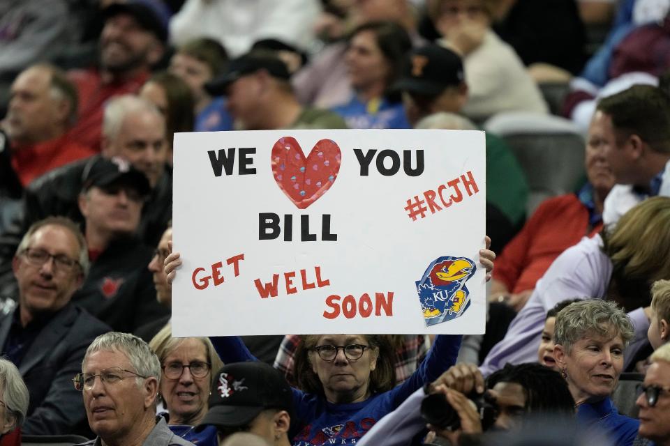 A fan holds up a get-well sign for Kansas head coach Bill Self during the first half of a college basketball game the Jayhawks were playing against West Virginia in the Big 12 Conference tournament on March 9 in Kansas City.