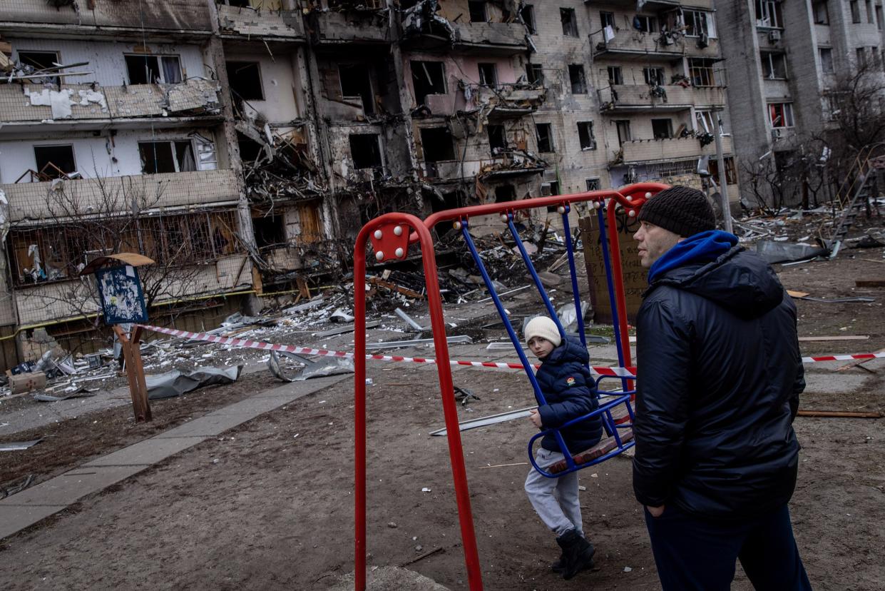 A boy plays on a swing in front of a damaged residential block hit by an early morning missile strike on Feb. 25, 2022, in Kyiv, Ukraine.