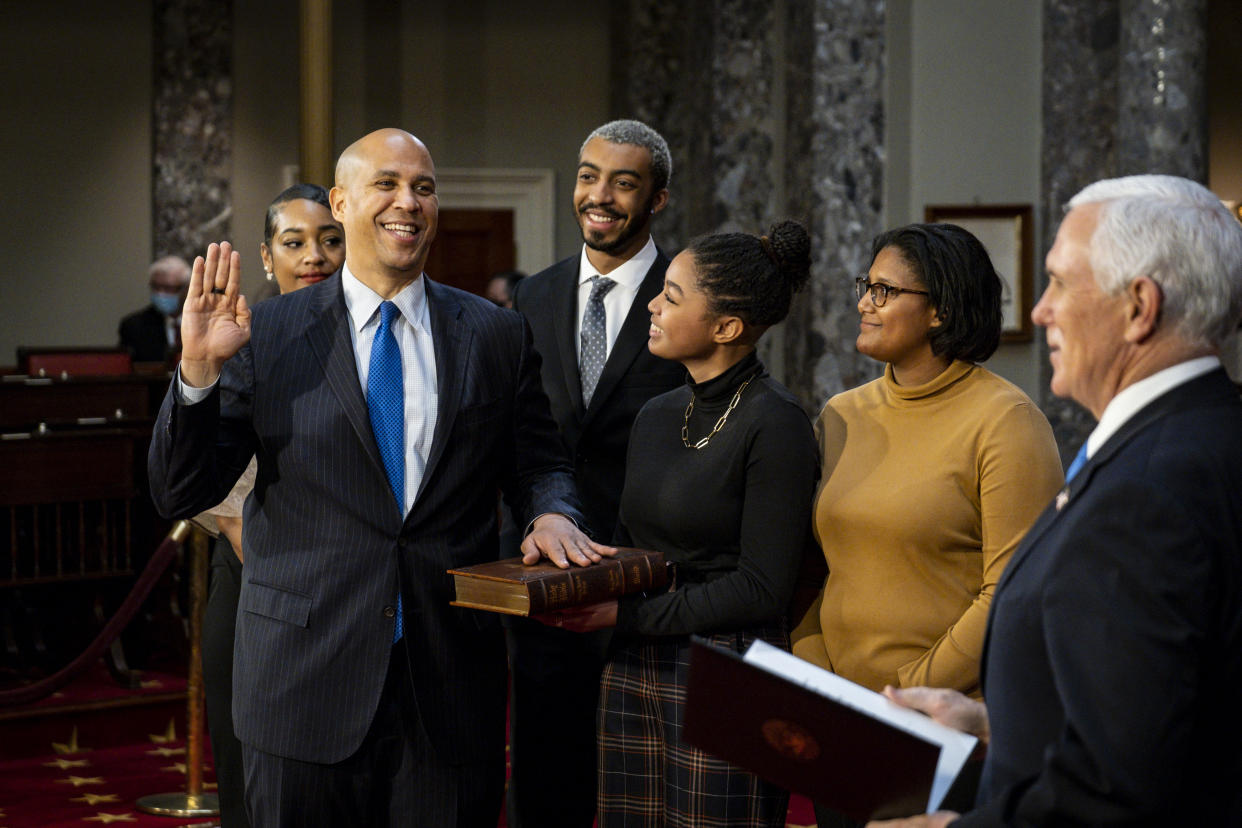 FILE - In this Jan. 3, 2021, file photo, Sen. Cory Booker, D-N.J., raises his hand to take the oath of office from Vice President Mike Pence during a reenactment ceremony in the Old Senate Chamber at the Capitol in Washington. The oath, which normally doesn’t attract much attention, has become a common subject in the final days of the Trump presidency, being invoked by members of both parties as they met Wednesday, Jan. 6, 2021 to affirm Biden's win and a pro-Trump mob stormed the U.S. Capitol. (Pete Marovich/The New York Times via AP, Pool, File)
